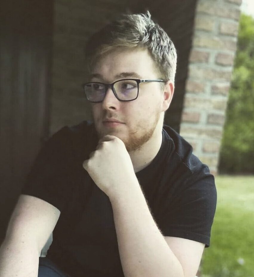 Beau mâle brun avec des lunettes portant un T-Shirt noir